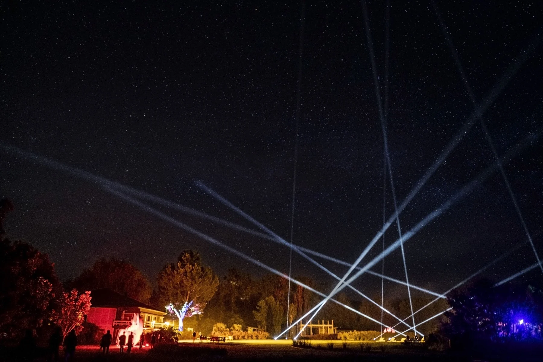 Haces de luz cruzan el cielo nocturno sobre el paisaje